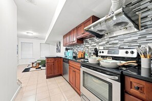 Eine moderne Küche mit Holzausstattung, einer Edelstahl-Dunstabzugshaube und einem eingebauten Ofen.