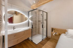 Ein modernes Badezimmer mit einer Duschkabine aus Glas, einem Holzwaschtisch und einem großen Spiegel.