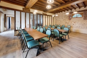 Ein Konferenzraum mit Holztischen und -stühlen, einer Steinwand und einer Holzzieldecke.