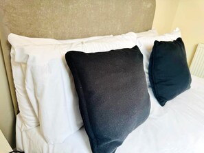 Ein Bett mit weißer Bettwäsche und zwei schwarzen Kissen.