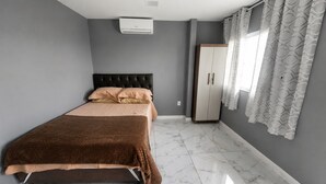 Un dormitorio con cama, armario y ventana con cortinas.