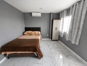 A bedroom with a bed, a wardrobe, and a window with curtains.