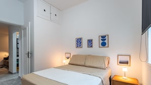 Un dormitorio con cama, mesitas de noche y decoración en la pared.