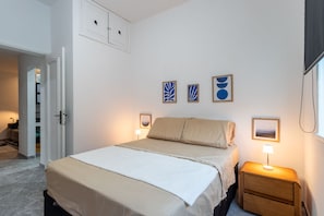 A bedroom with a bed, bedside tables, and wall art. - Apto Beira-mar com Ar Condicionado em Copacabana (Rio de Janeiro)