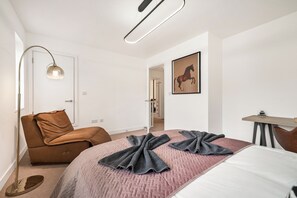 Ein modernes Schlafzimmer mit einem Bett, einem braunen Sessel, einer Stehlampe und einem Gemälde von einem Pferd an der Wand.