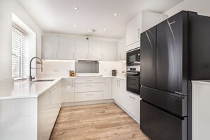 A modern kitchen with white cabinetry, a black refrigerator, and a built-in oven.