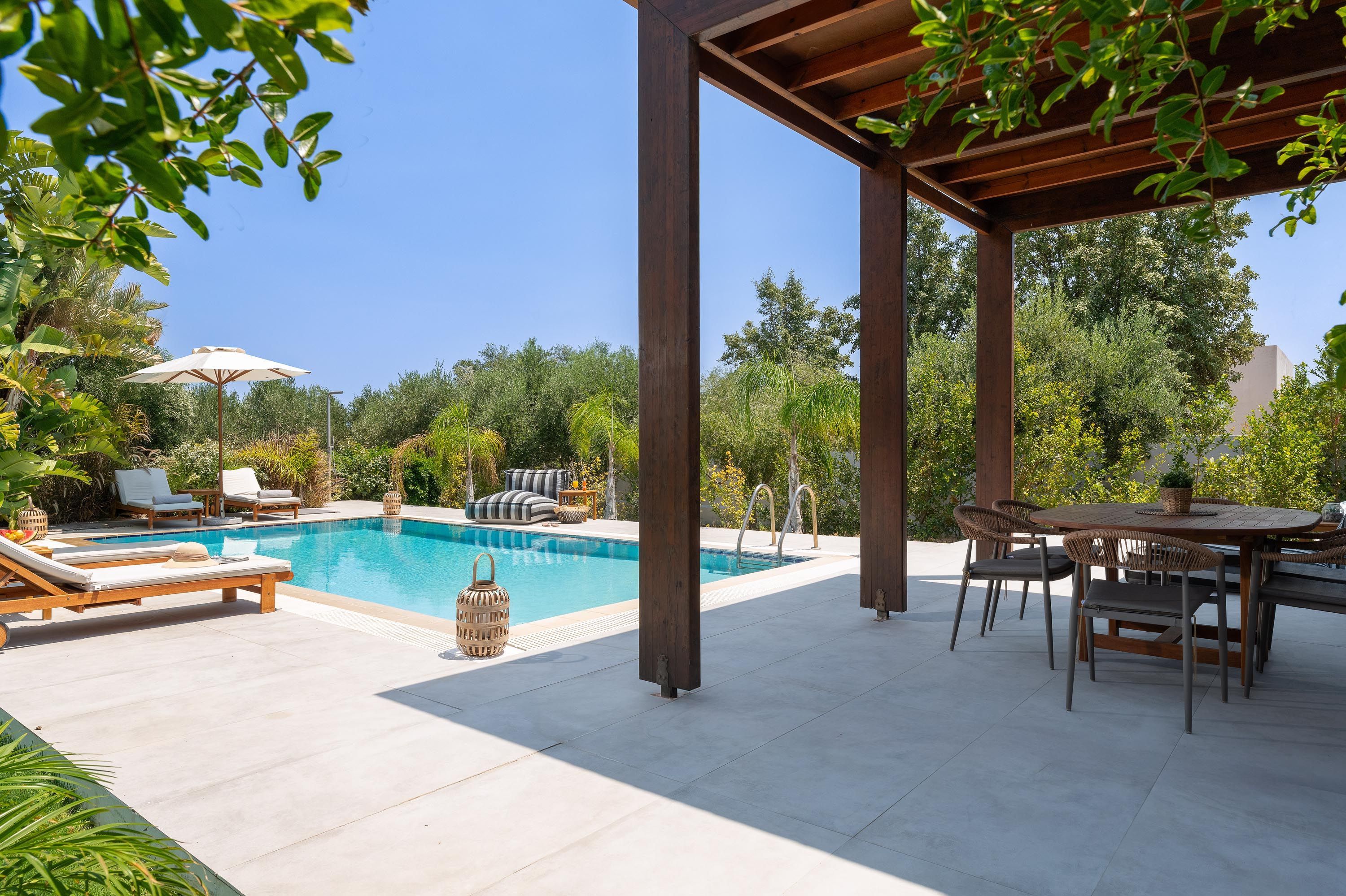 Un espace piscine aménagé avec des chaises longues, une table et une pergola.