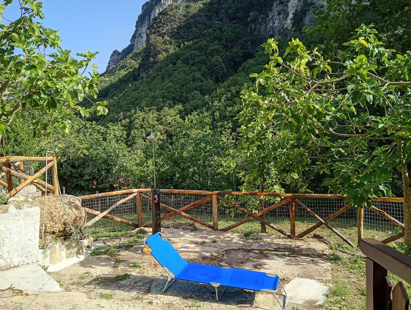 Ein blauer Liegestuhl in einem Außenbereich mit Holzzaun und Bergblick.