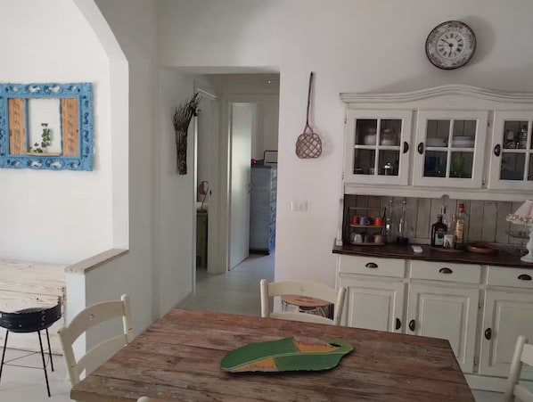 A kitchen with white cabinets, a wooden table, and a hanging clock.