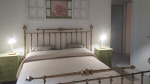 A bedroom with a bed, two bedside tables, a wall-mounted picture, and a door. - Selvaluna . (Campania)