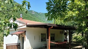 A single-story house with a red-tiled roof, a covered porch, and a hammock. - Selvaluna . (Campania)