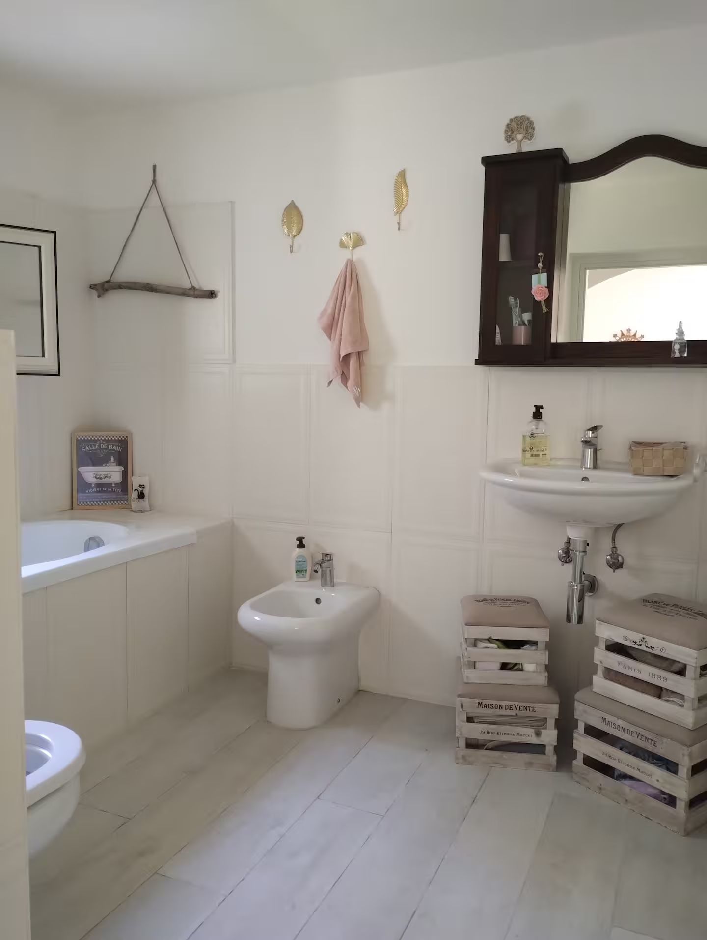 Ein Badezimmer mit Badewanne, Bidet und Waschbecken. An den Wänden befinden sich Dekorationen und ein Spiegel über dem Waschbecken.
