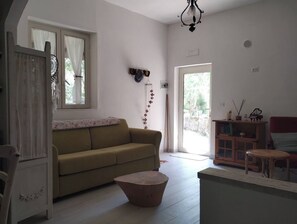 A living room with a sofa, a coffee table, a wooden cabinet, and a door leading outside.