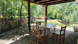 An outdoor patio with a table and chairs, surrounded by a stone wall and trees. - Selvaluna . (Campania)