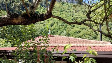A building with a red-tiled roof, surrounded by lush greenery and trees.