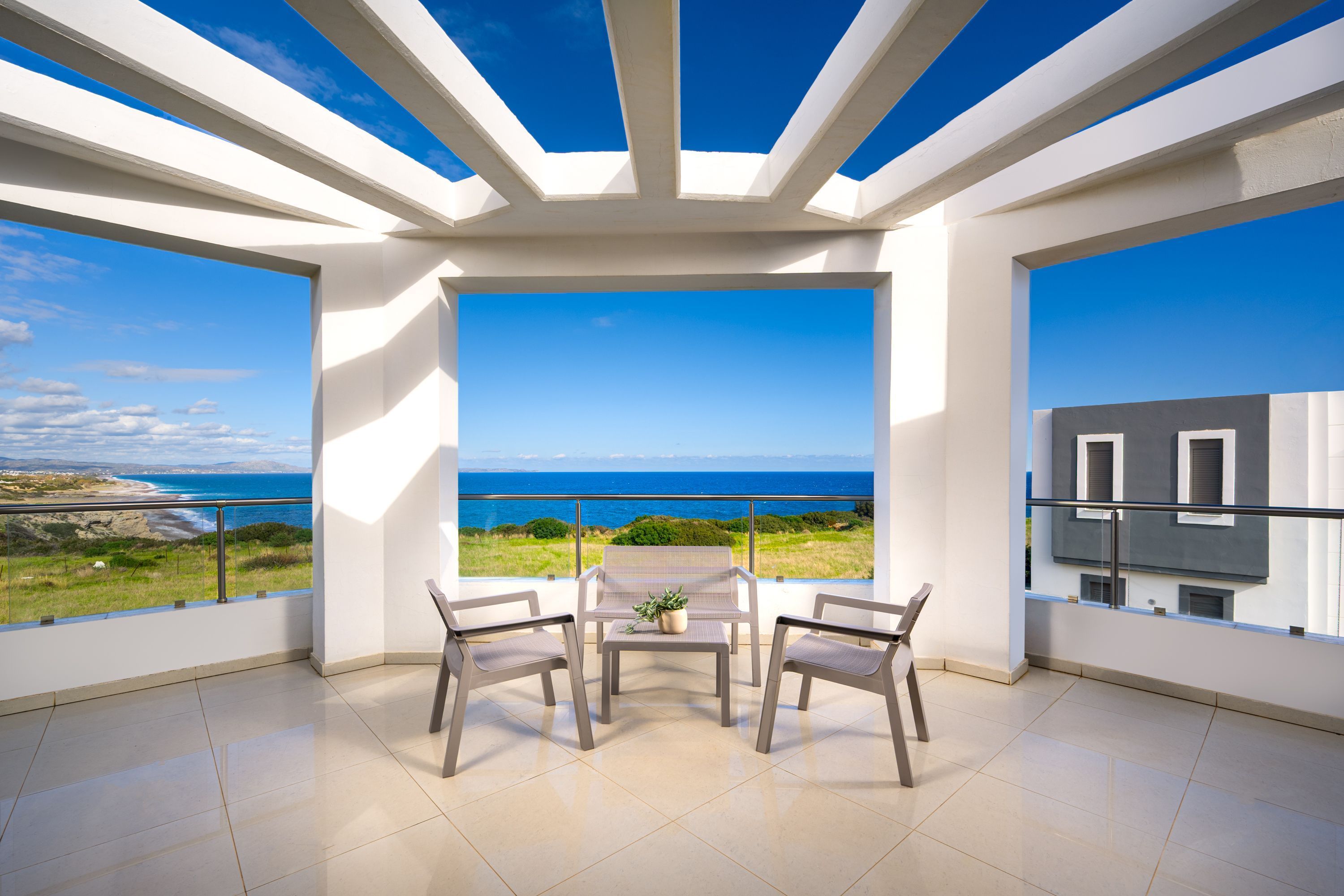Ein Balkon mit Tisch und Stühlen mit Blick auf eine Küstenlandschaft.