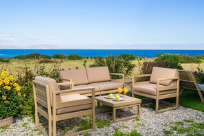An outdoor seating area with a sofa and chairs, a table with fruit and drinks, and a view of the sea. - Villa Aqua in Lachania (Lachania)