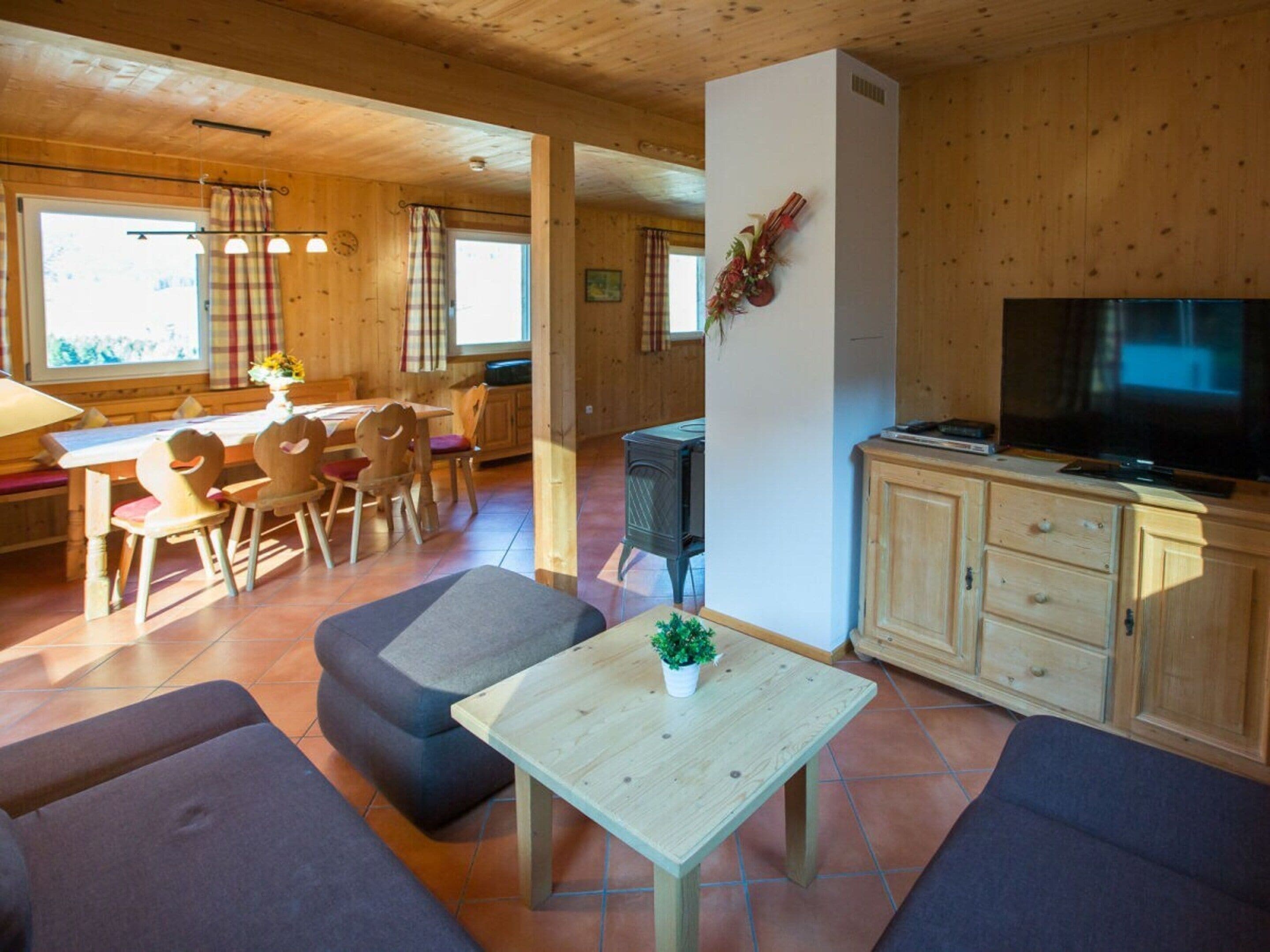 Ein Holzinnenraum mit Essbereich, einer Couch, einem Fernseher und einem Kamin.