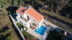 Ein zweistöckiges Haus mit Swimmingpool, Terrasse und Steinmauer.