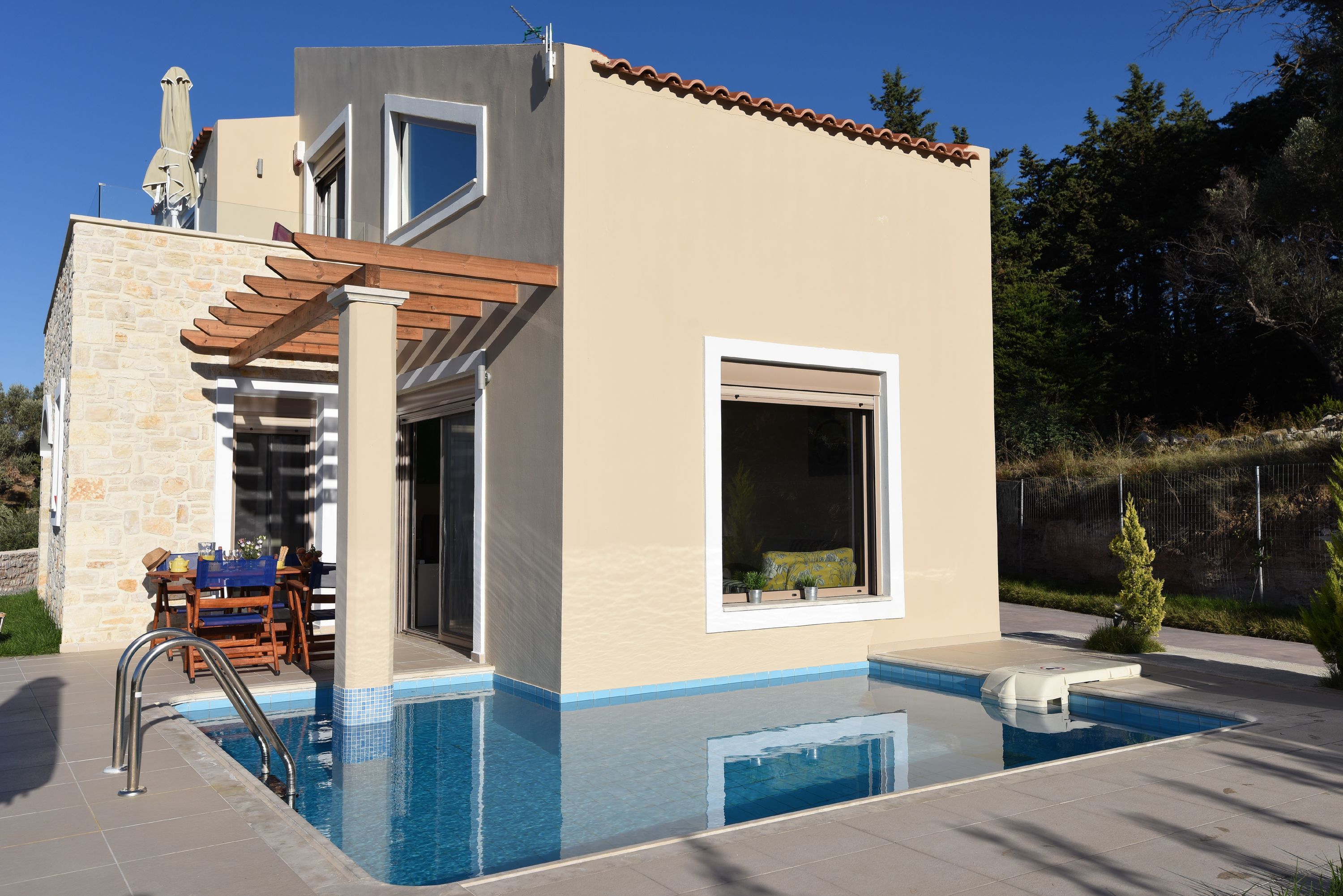 A modern house with a swimming pool, stone walls, and a pergola.