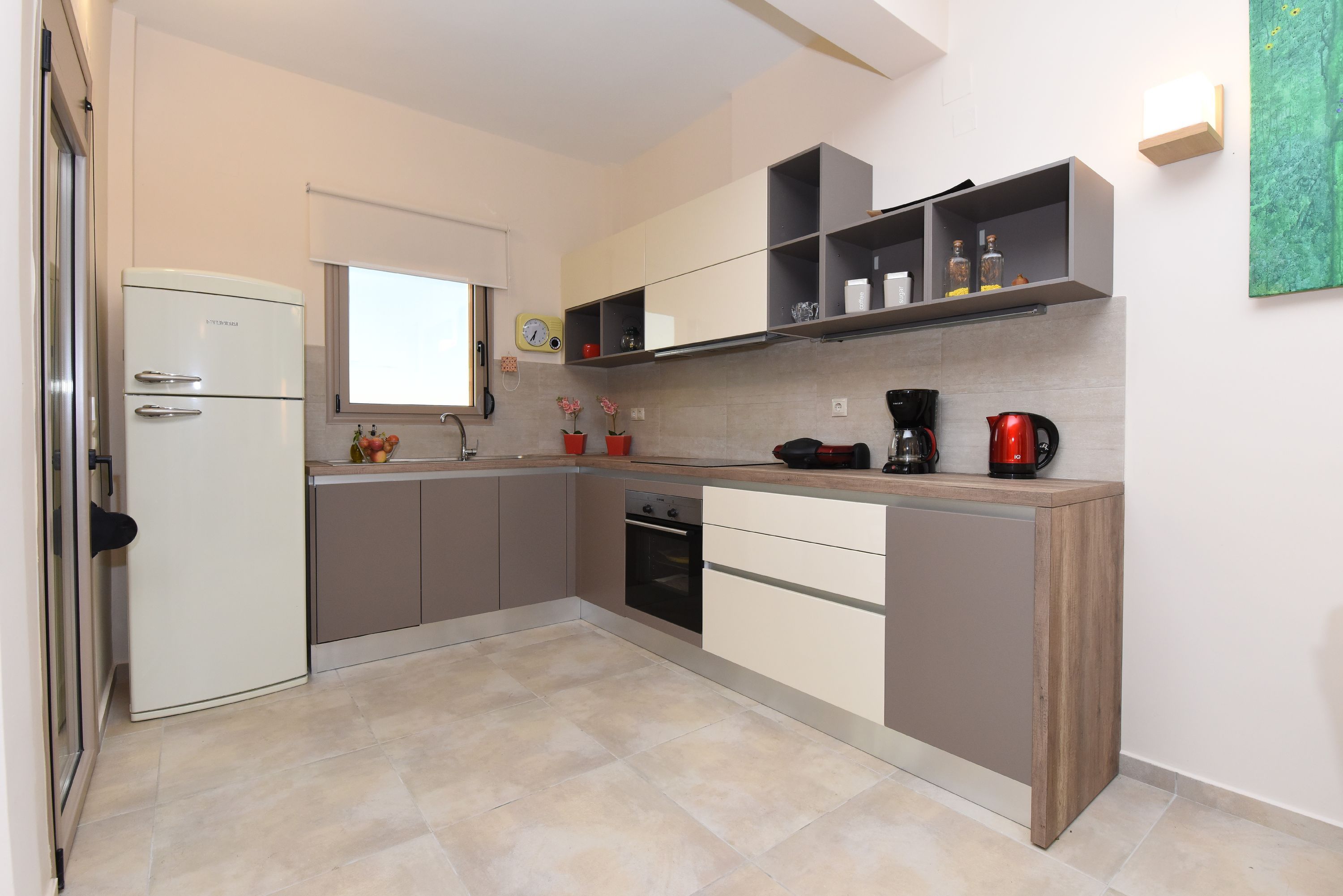 A compact kitchen with a built-in oven, a refrigerator, and a coffee maker.