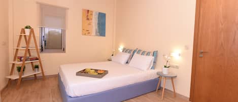 A bedroom with a bed, bedside table, lamp, window, and a wooden ladder.