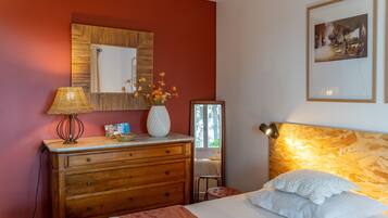 A room with a bed, a dresser, a mirror, a lamp, and a framed picture on the wall.