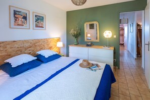 A bedroom with a bed, a dresser, a mirror, and a hallway leading to another room.