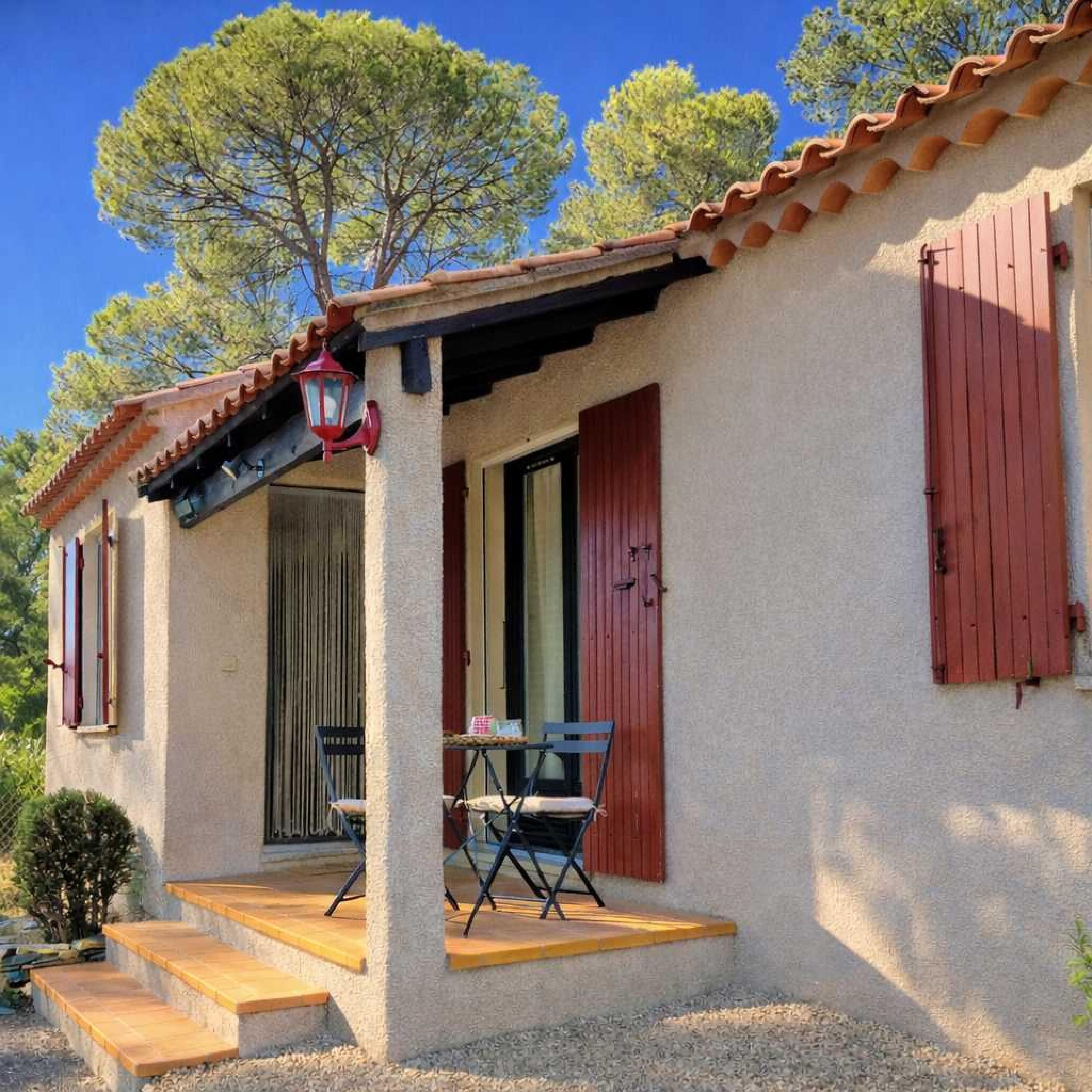 Ein Gebäude mit einer Veranda, einem Tisch und Stühlen sowie einer roter Tür.