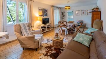 Un salon confortable avec un canapé, des fauteuils, un téléviseur et un coin repas comprenant des chaises et une table.