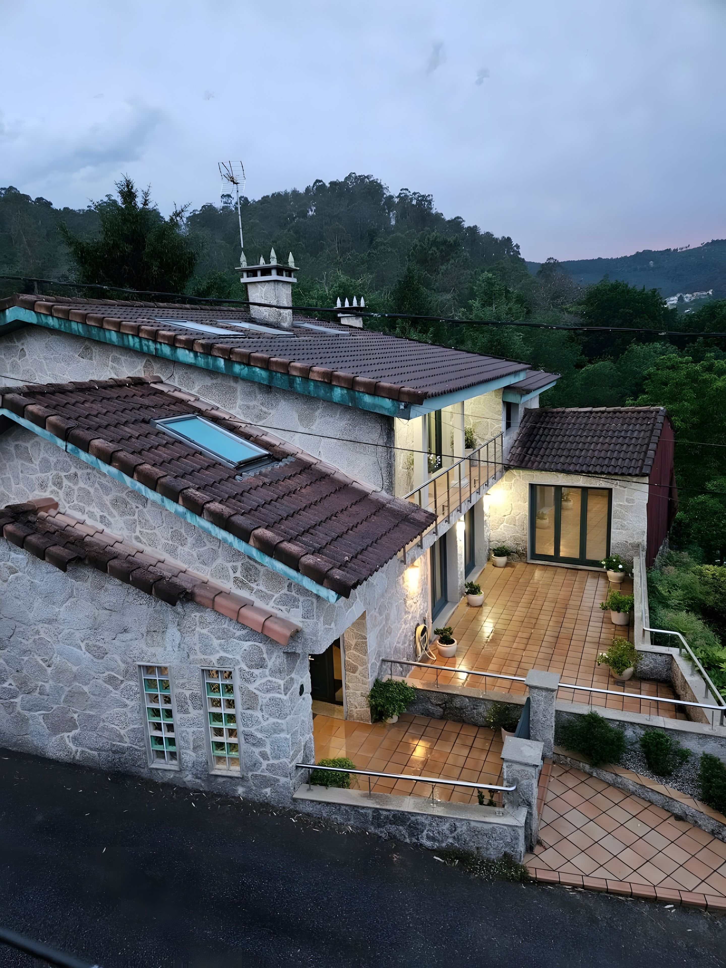 Una casa de varios pisos con fachada de piedra, techo de tejas y un balcón.