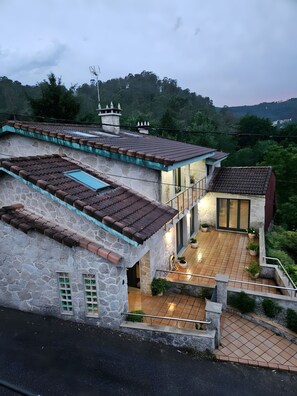 Una casa de diversos pisos amb façana de pedra, teulada de teules i un balcó.