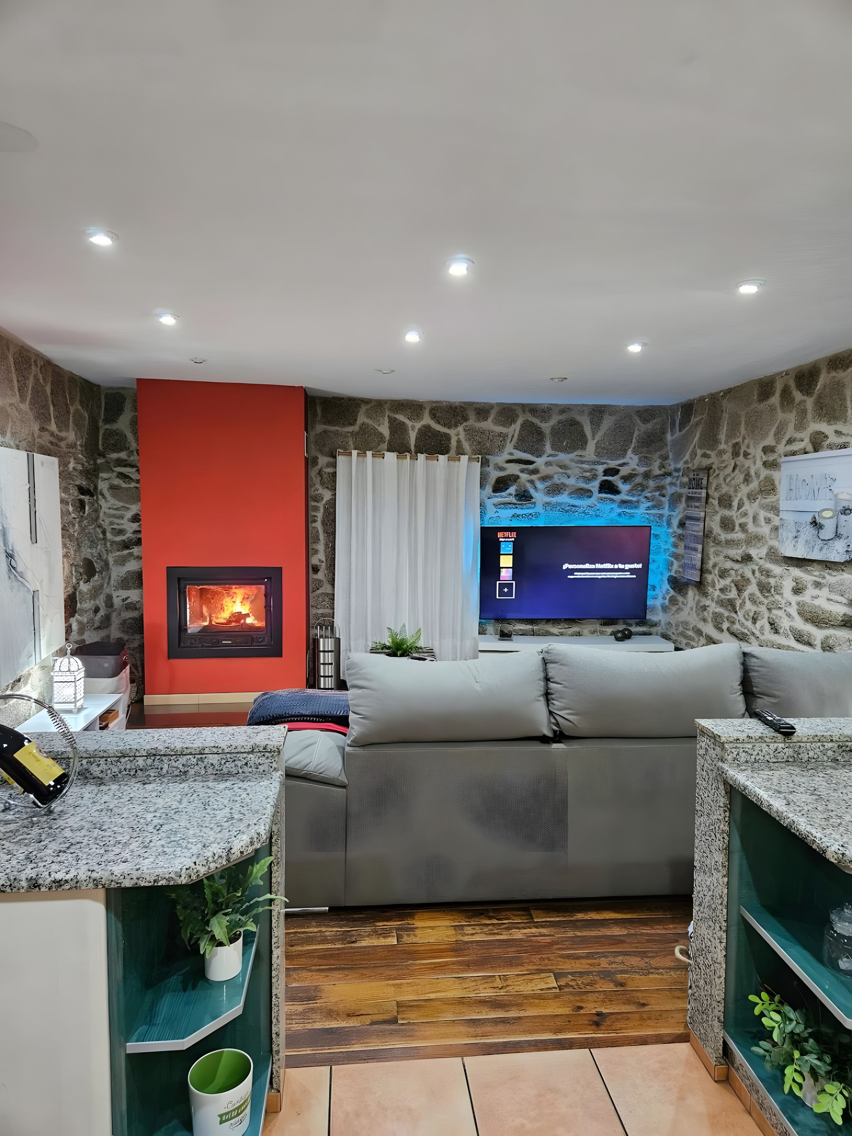 Una sala de estar con pared de piedra, chimenea, televisor y sofá.