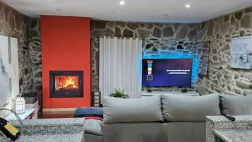 A living room with a stone wall, a fireplace, a television, and a sofa.