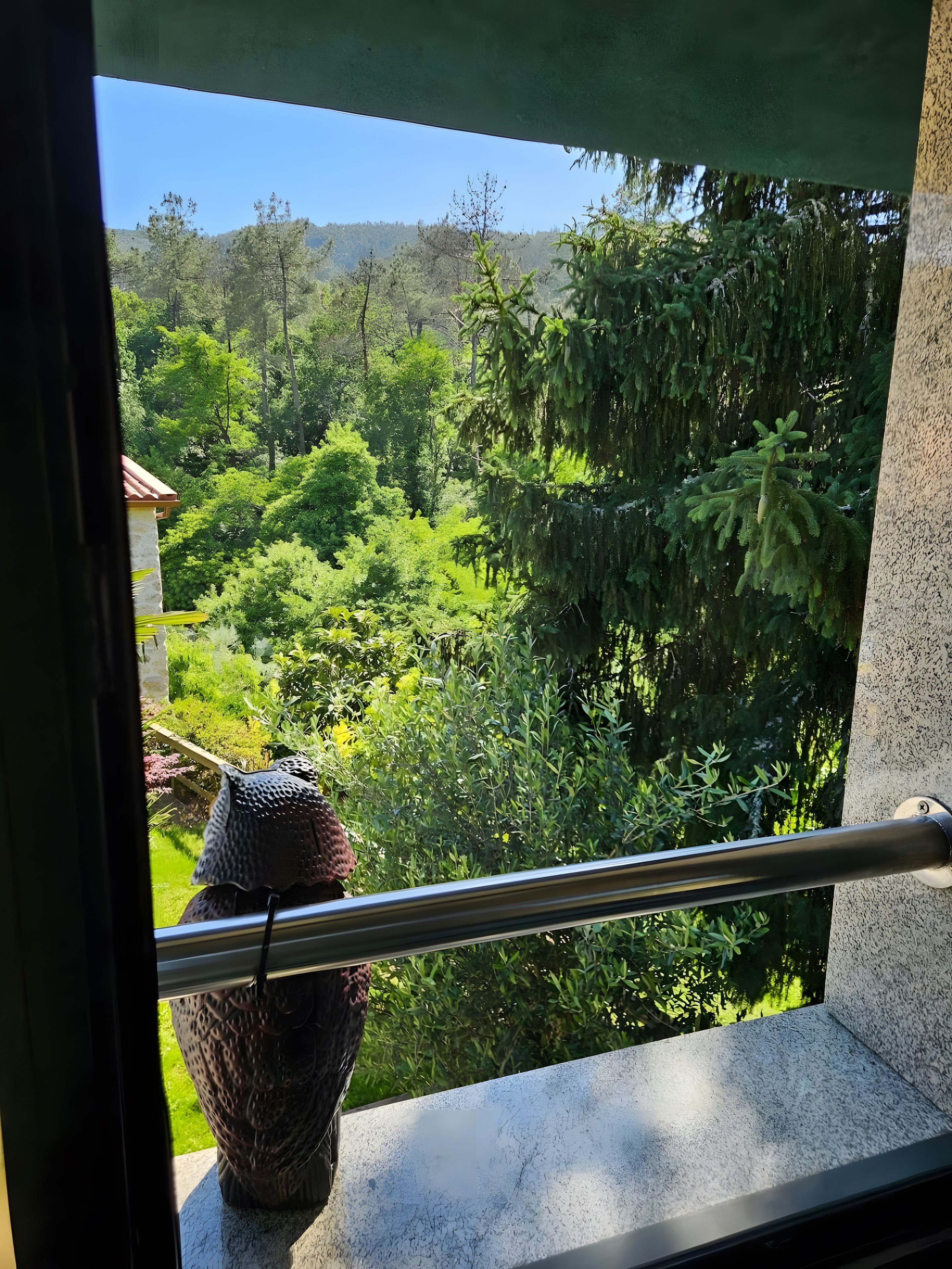 Un balcón con vistas a una vegetación exuberante y una estructura de piedra.