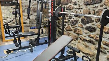 A gym with a stone wall, a bench, and various exercise equipment.