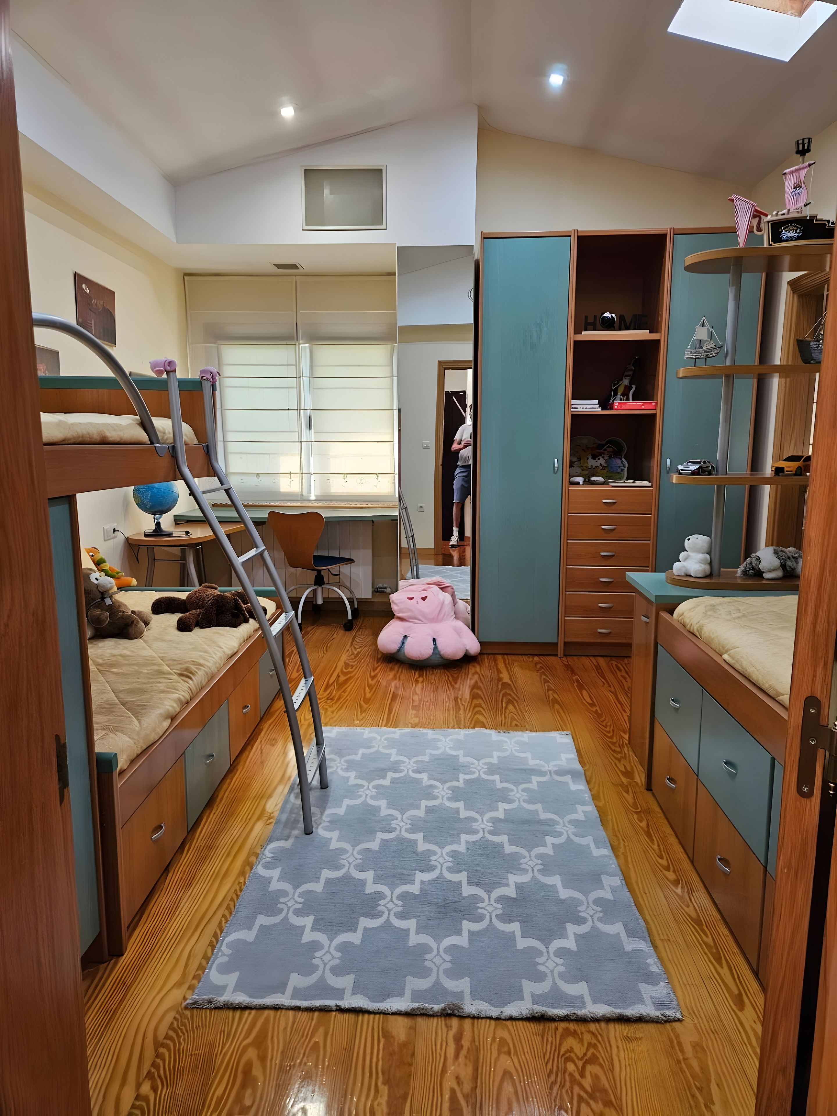 Un dormitorio pequeño con literas, un escritorio y un armario.