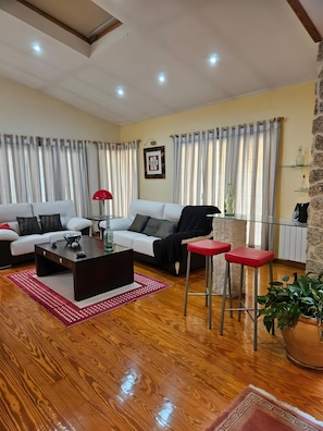 Una sala de estar con un sofá, una mesa de centro, una lámpara roja y una planta en maceta.