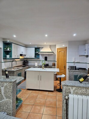 Una cocina moderna con encimeras de granito, armarios blancos y una isla central.