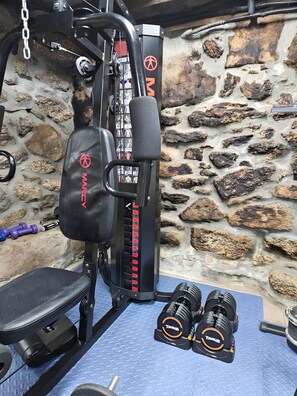 Un gimnasio en casa con una bicicleta estática, mancuernas y un banco.