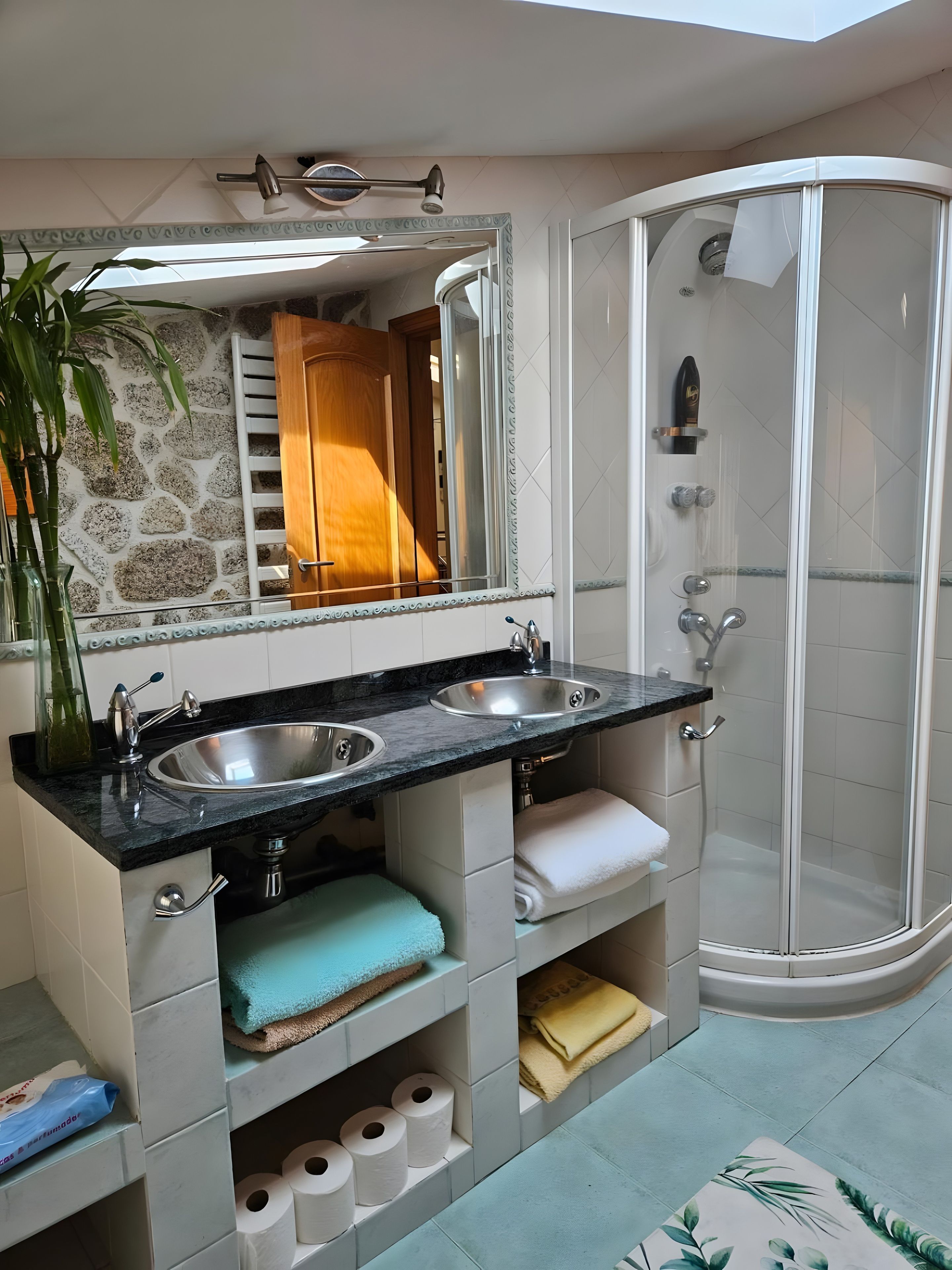 A bathroom with a double sink, a glass shower enclosure, and a mirror with a decorative frame.