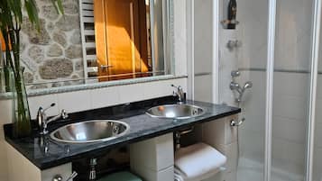 A bathroom with a double sink, a glass shower enclosure, and a mirror with a decorative frame.