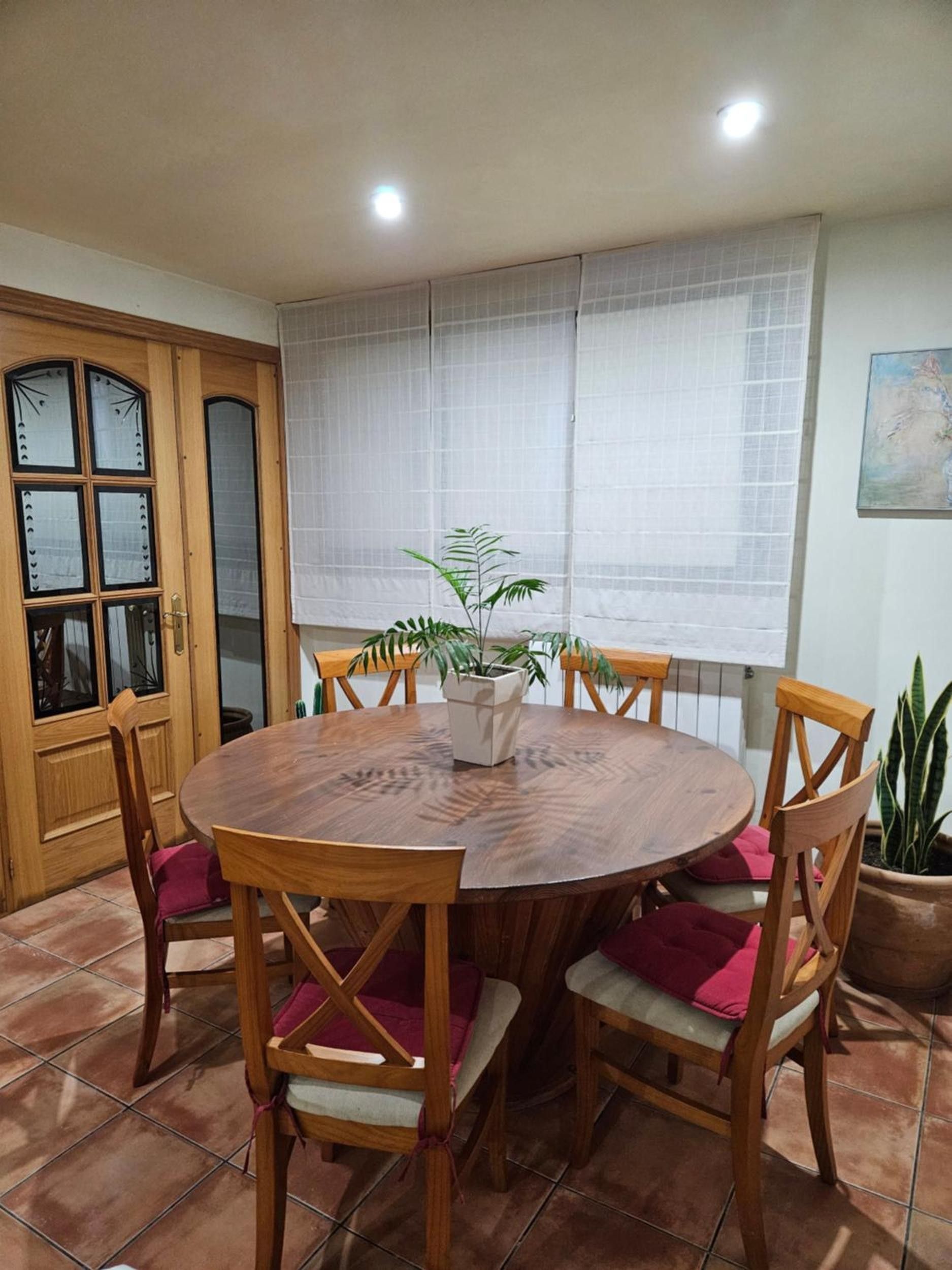 A dining area with a round wooden table surrounded by wooden chairs with cushioned seats.