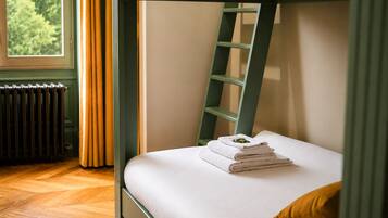 Un lit superposé avec une échelle, un radiateur et une fenêtre avec des rideaux.