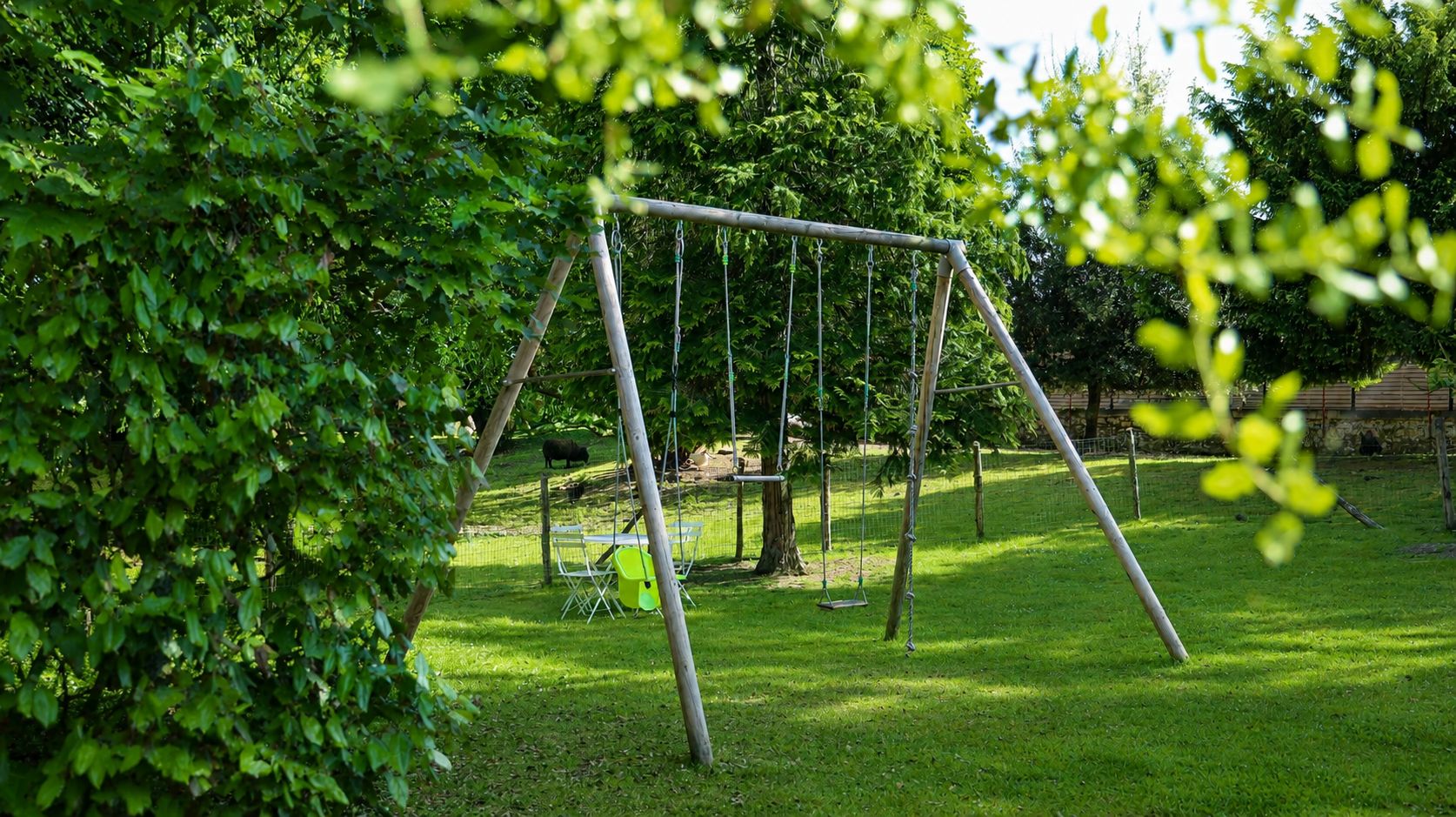 A swing set in a grassy park area with trees.