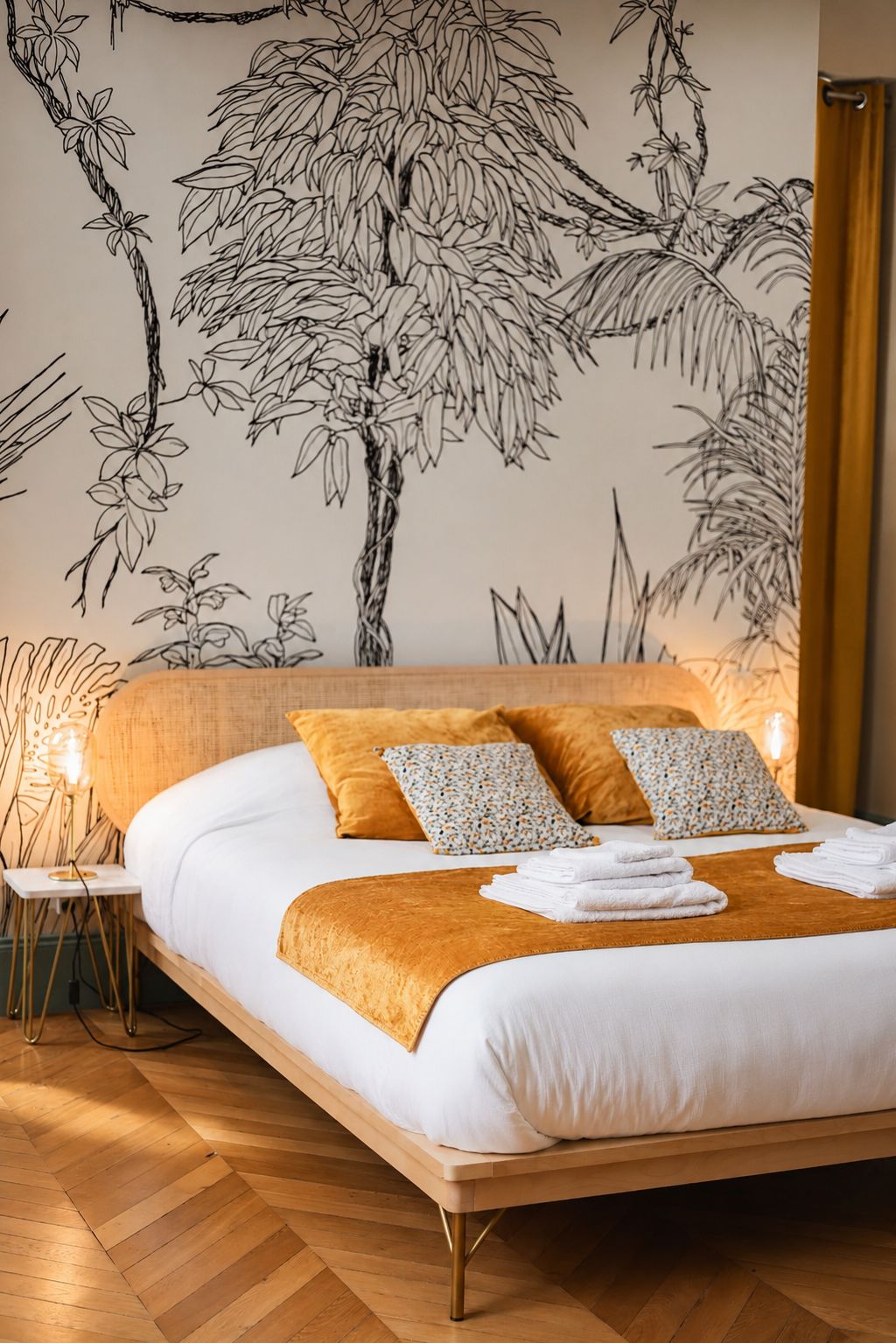 A bedroom with a bed, pillows, a bedside table, and a wall mural.