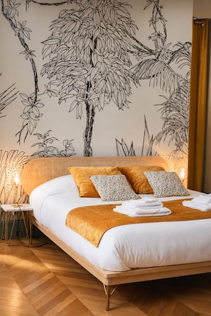 A bedroom with a bed, pillows, a bedside table, and a wall mural.