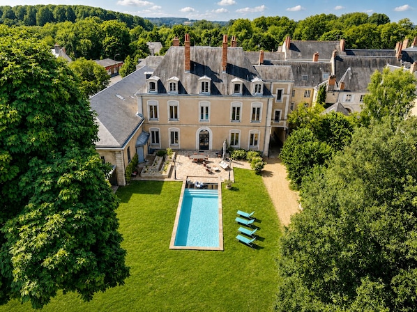 A large estate with a swimming pool, multiple buildings, and lush greenery.