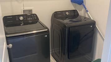 A laundry area with two washers and dryers, a mop, and a basket.