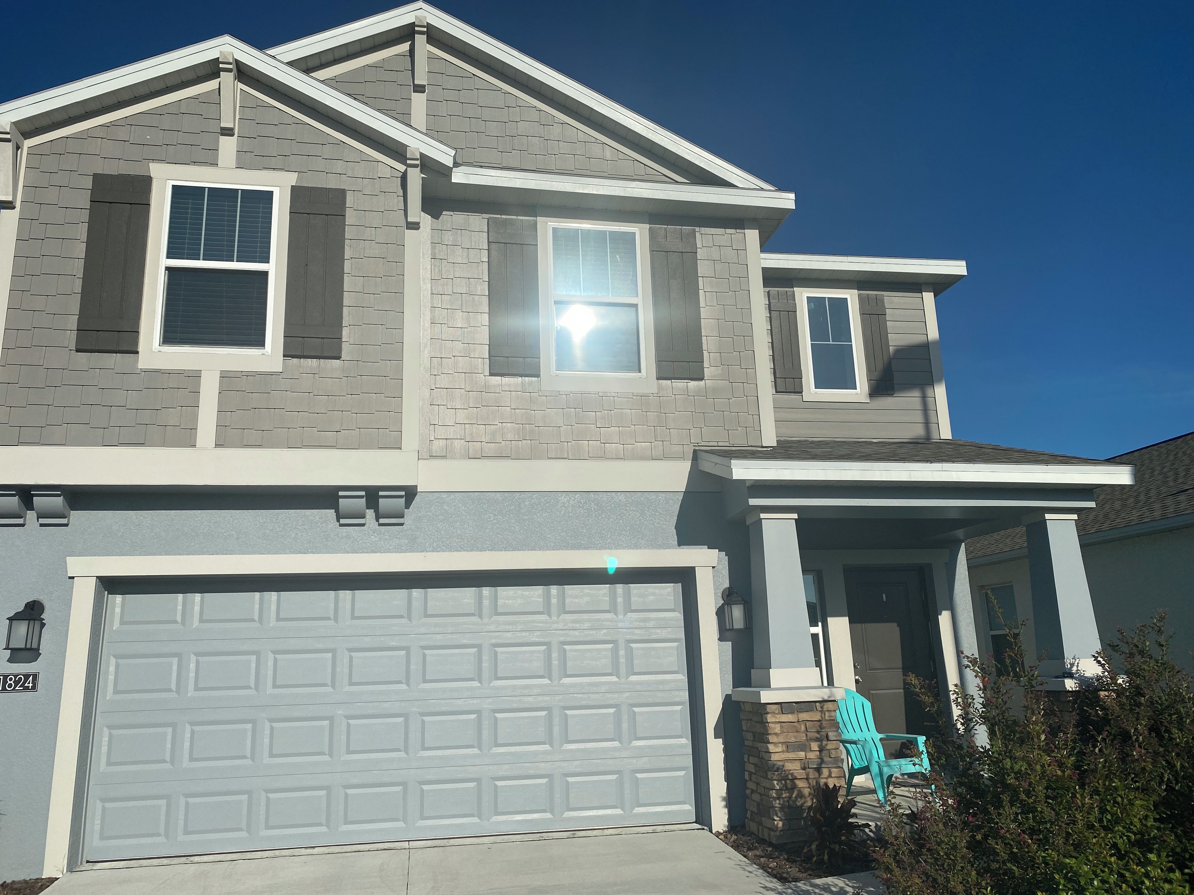 A two-story house with a garage, a covered porch, and a small front yard.